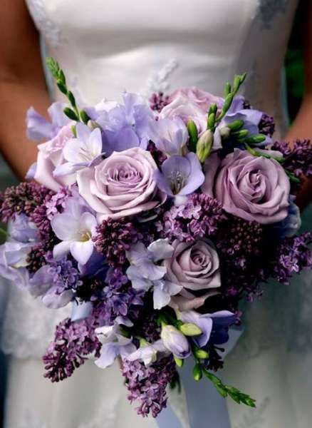 a bride holding a bouquet of purple flowers