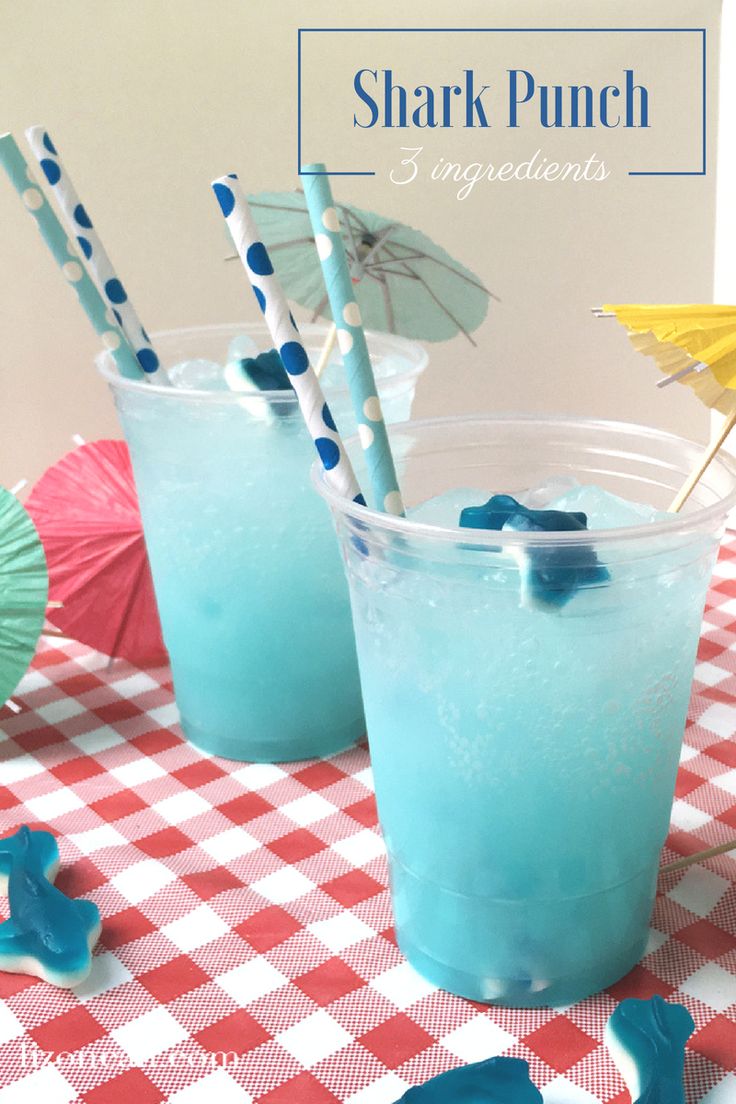 two glasses filled with blue liquid sitting on top of a checkered tablecloth covered table