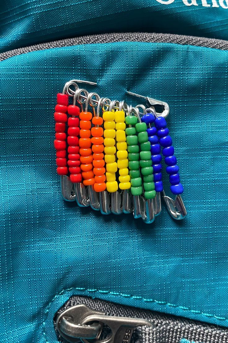 there is a small rainbow pin on the back of a blue bag with zippers