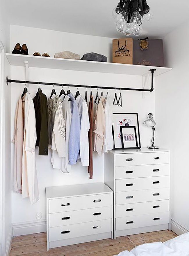 an organized closet with white drawers and hanging clothes