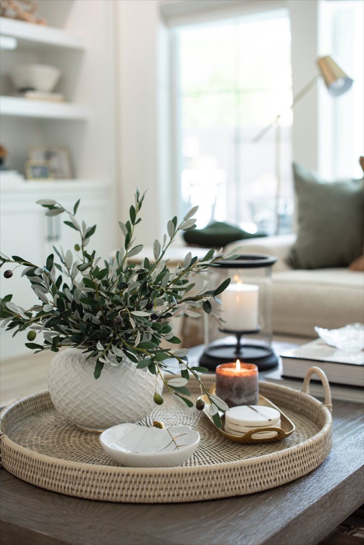 a living room with a coffee table and vase on it's tray, candles in the background