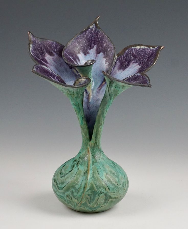 a green vase with purple flowers in it