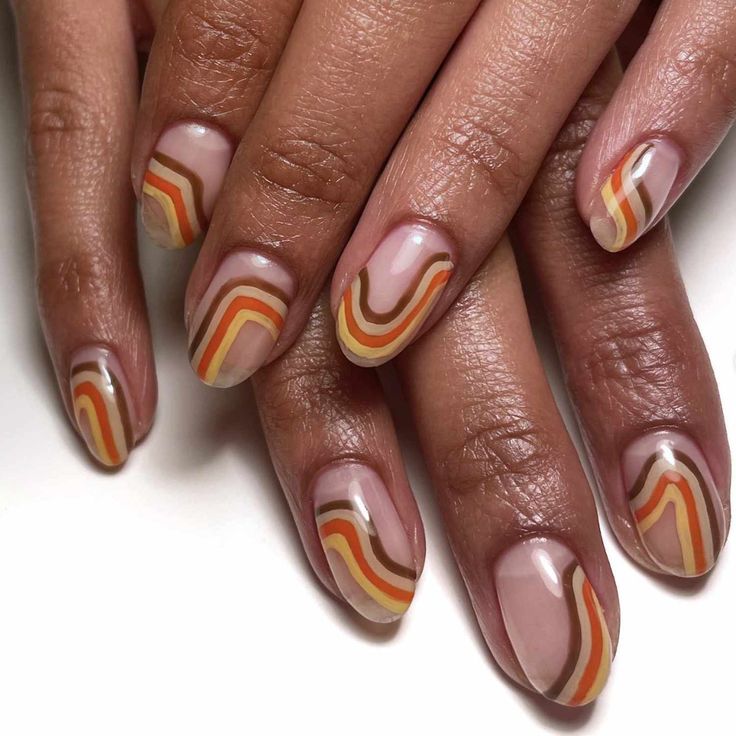 a woman's nails with orange and white designs on them