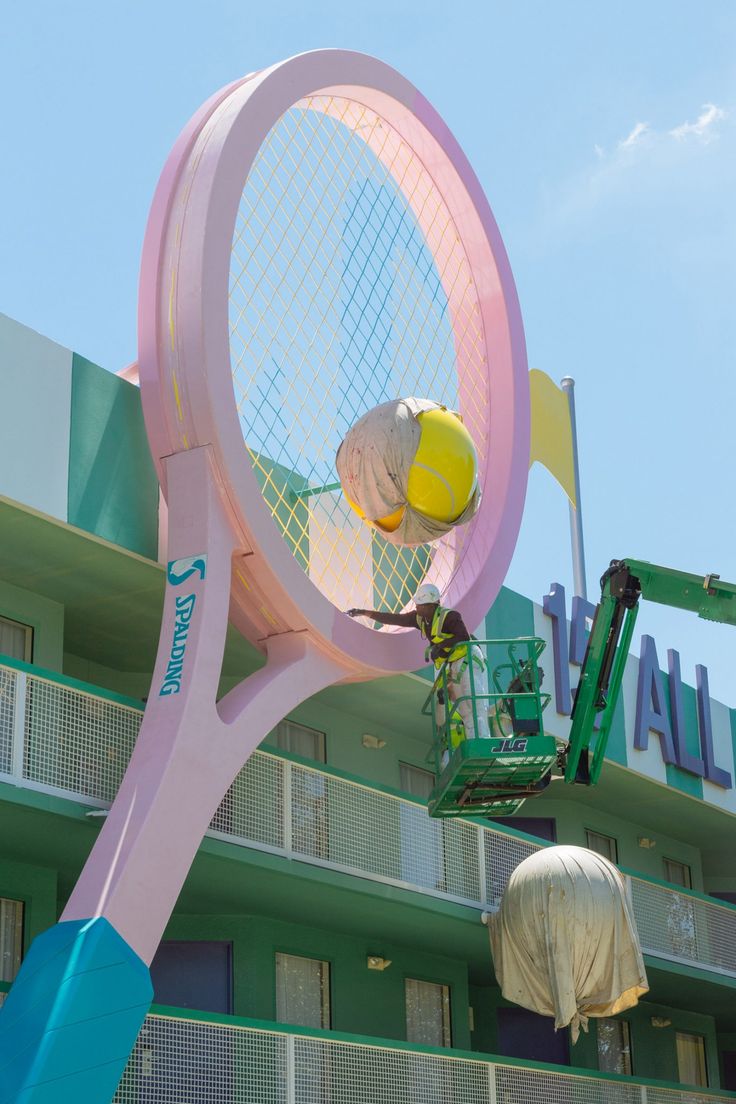 there is a giant pink tennis racket in front of the building that has it's name on it