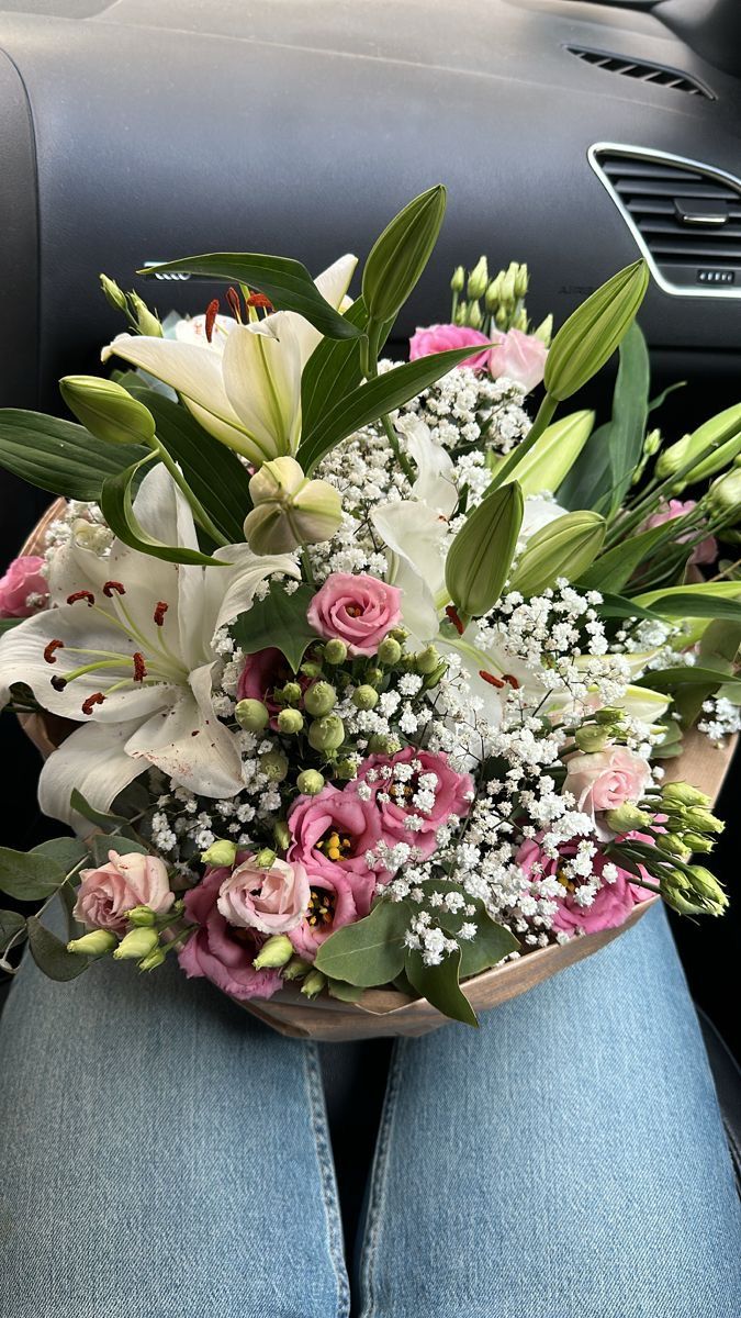 a bouquet of flowers sitting on the back seat of a car in someone's lap
