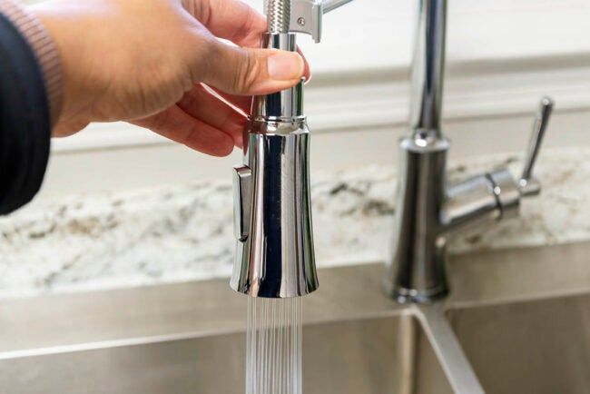 a person is holding the faucet in front of a sink with water running from it