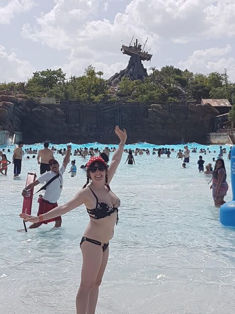 a woman is standing in the water at an amusement park with other people around her