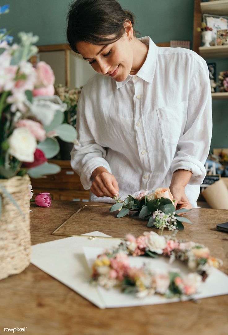 a woman in white shirt arranging flowers on table