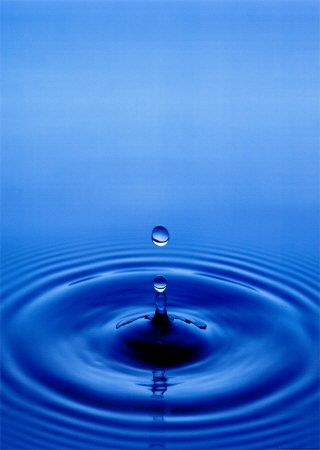 a blue water droplet in the middle of a body of water with ripples
