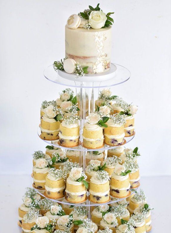 a three tiered cake and cupcake display with flowers on each tier is shown