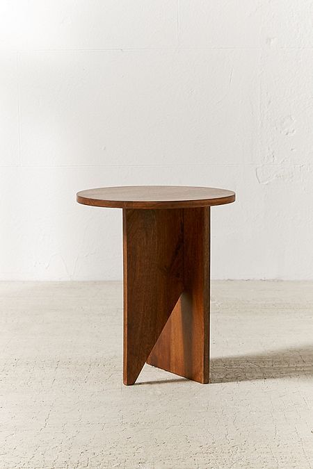 a round wooden table sitting on top of a white floor