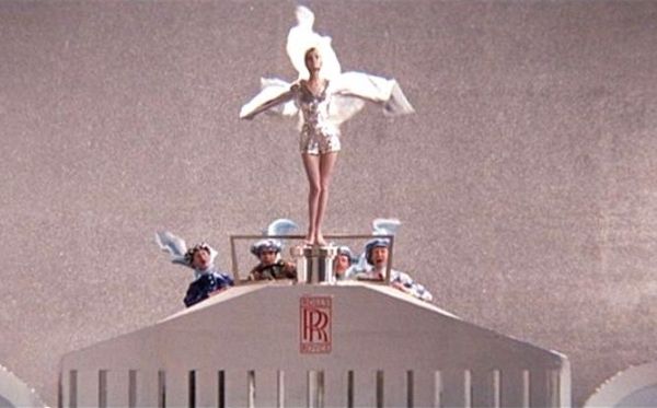 there is a statue on top of a building with people in uniform around it and one woman standing on the roof