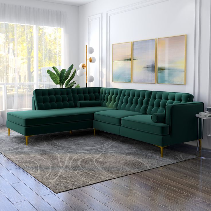 a green couch sitting on top of a hard wood floor next to a painting and rug