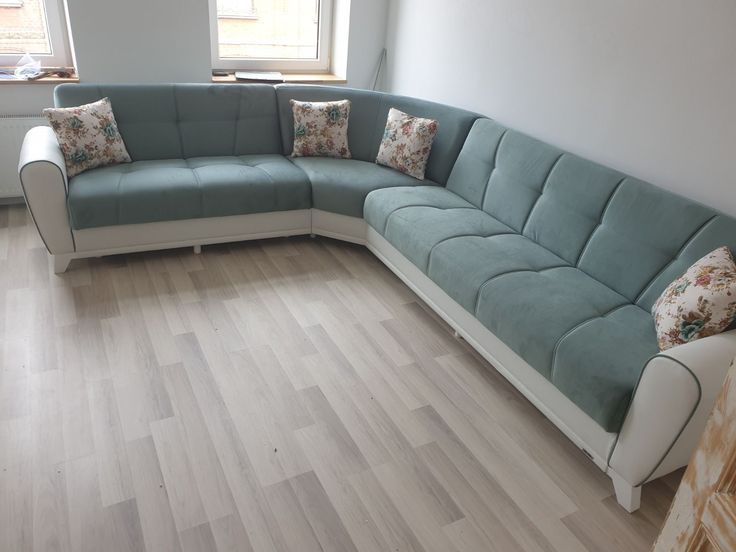 a blue sectional couch sitting on top of a hard wood floor