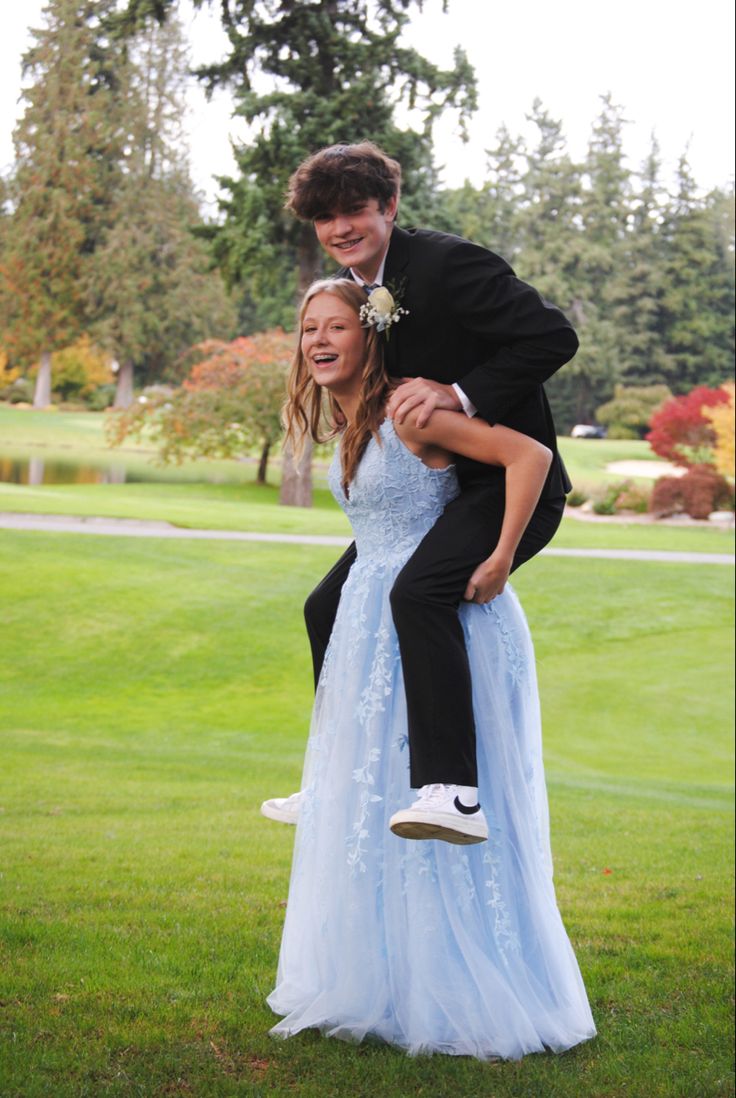 a man in a tuxedo is being carried by a woman in a blue dress