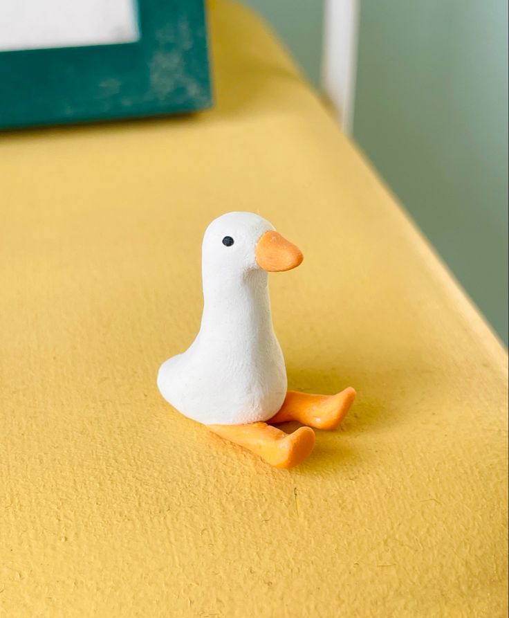 a small white duck sitting on top of a bed