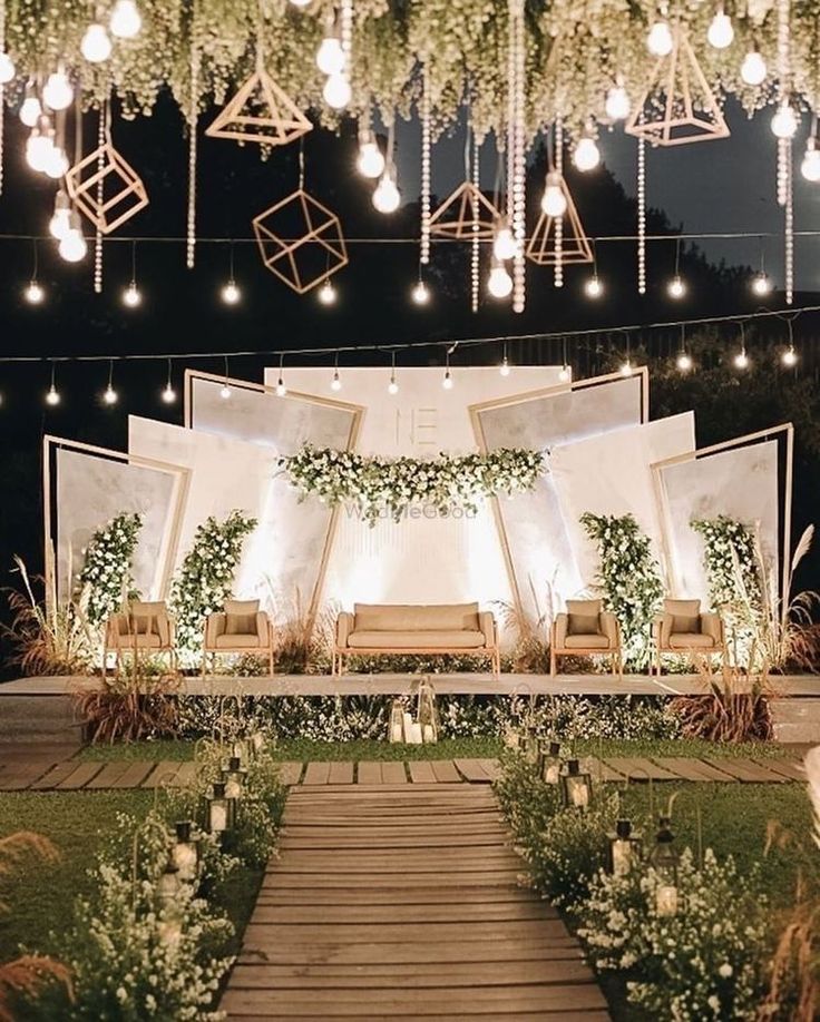 an outdoor wedding setup with white flowers and greenery hanging from the ceiling above it