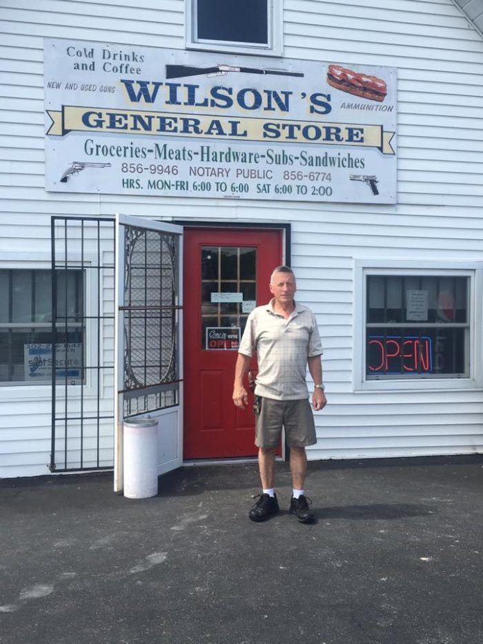 a man standing in front of a building with a red door and sign that says wilson's general store