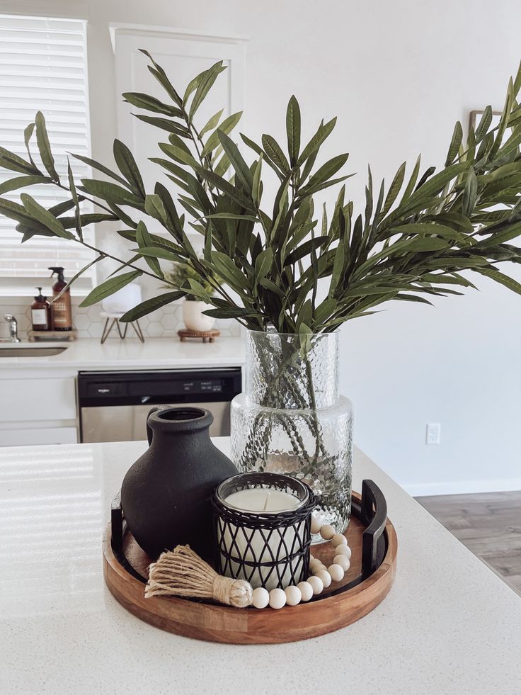 there is a vase with some plants in it on the kitchen counter top, next to a candle holder