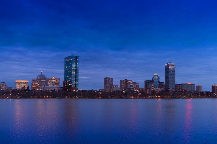 the city skyline is lit up at night by the water's edge, with skyscrapers in the distance