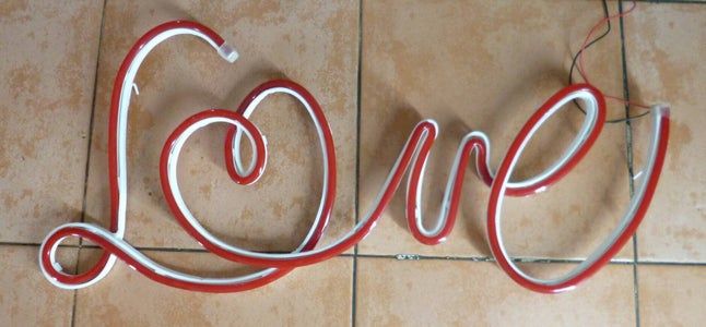 a red and white love sign sitting on top of a tiled floor