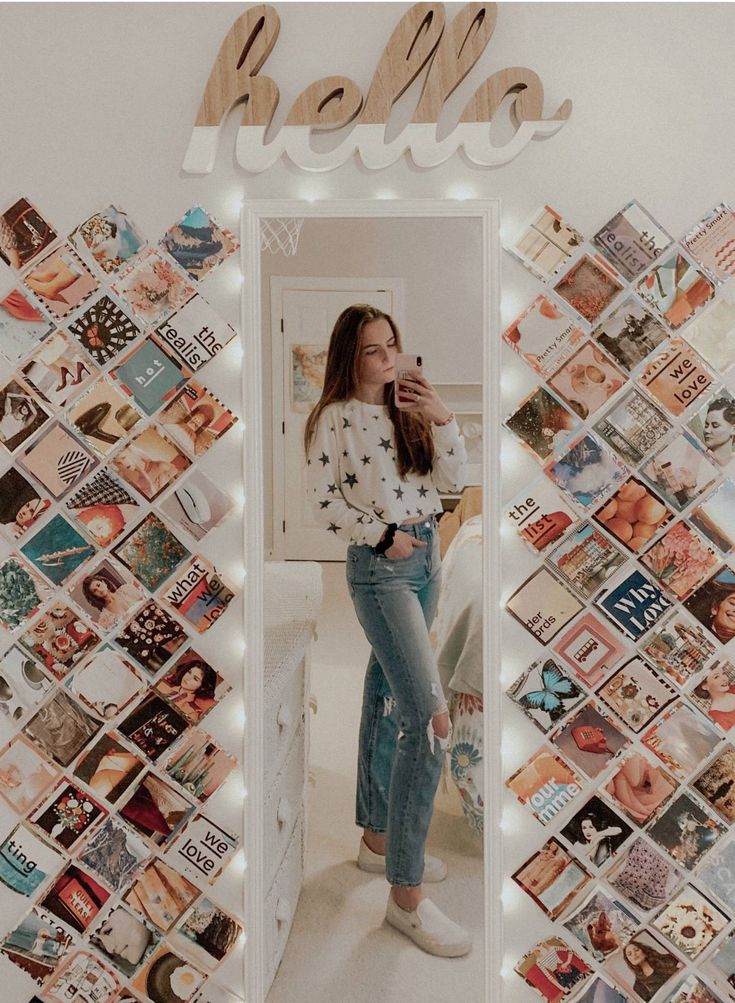 a woman standing in front of a mirror with pictures on the wall behind her and words above it