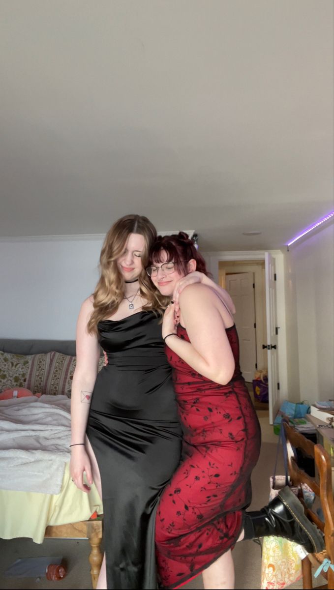 two women standing next to each other in a room with a bed on the floor
