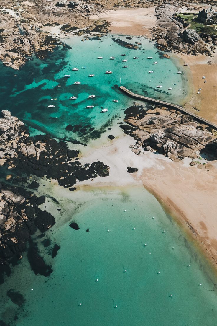 an aerial view of the ocean and beach with boats floating in it's water