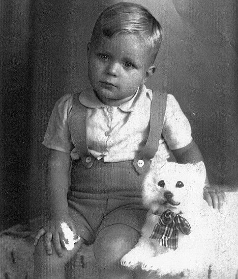 an old black and white photo of a little boy with a teddy bear in his lap