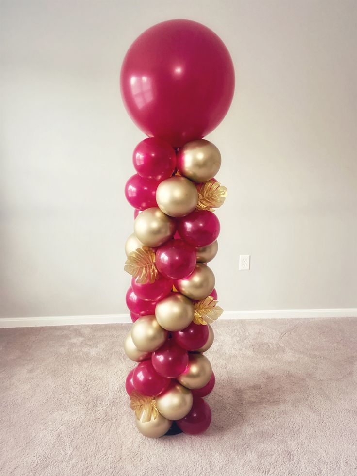 a bunch of balloons that are in the shape of a tower with gold and pink balls