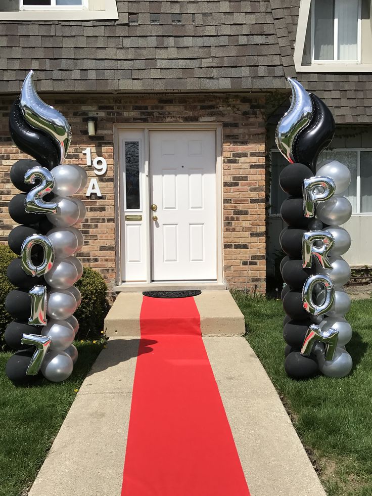 an entrance to a house with balloons and streamers on the red carpet in front