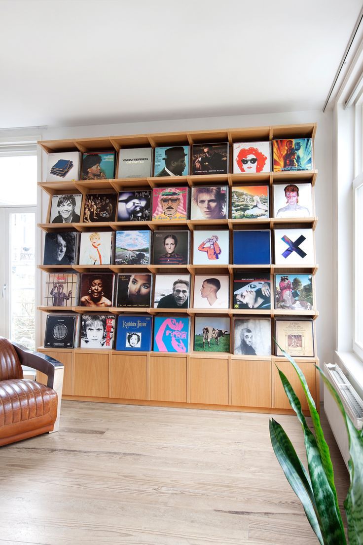 a living room with a book shelf filled with books and vinyl records on the wall