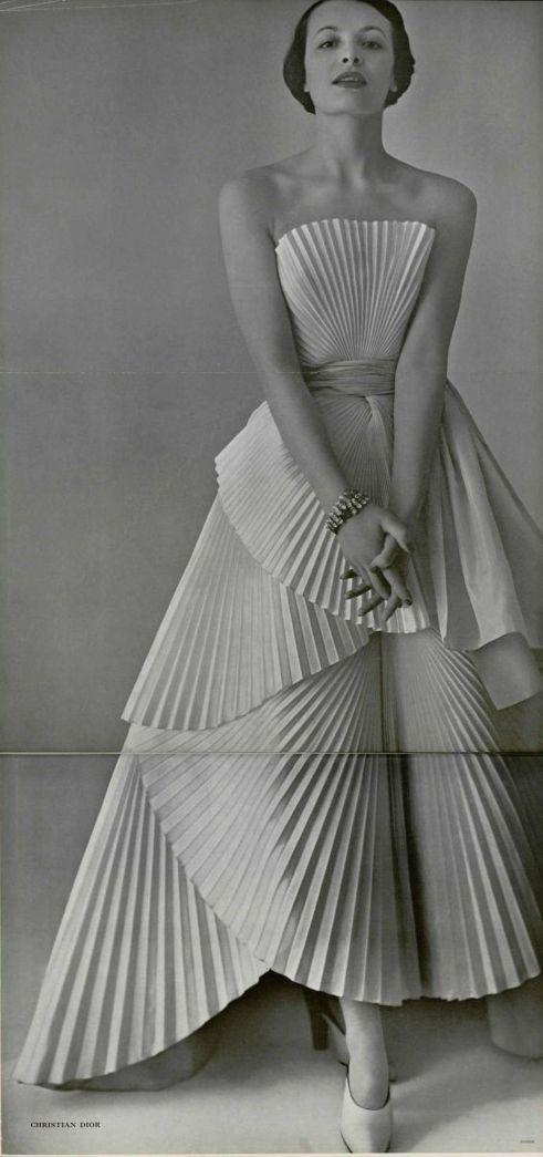 a black and white photo of a woman in a dress made out of folded paper