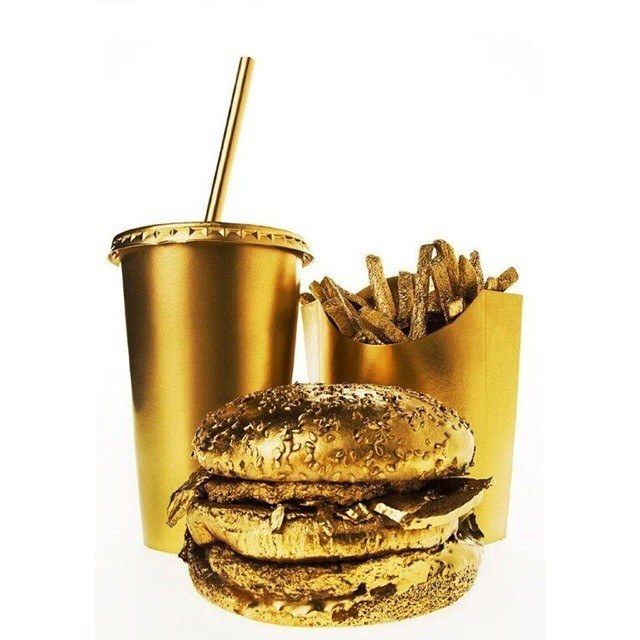 a hamburger and fries are sitting next to each other in front of a gold cup