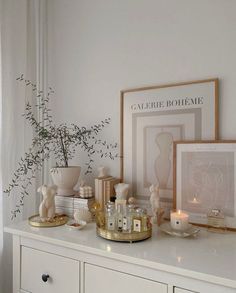 a white dresser topped with pictures and candles