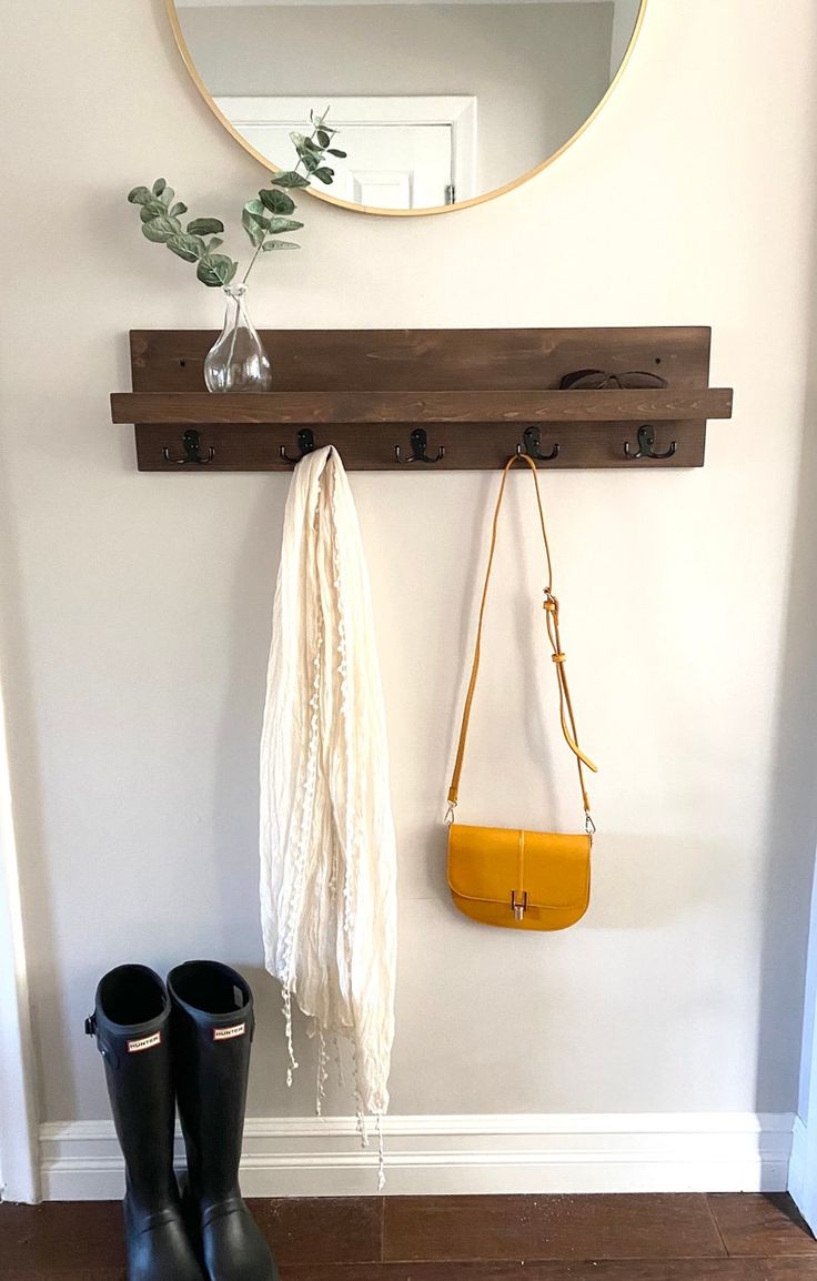 a pair of black rain boots hanging on a wall next to a mirror and purse