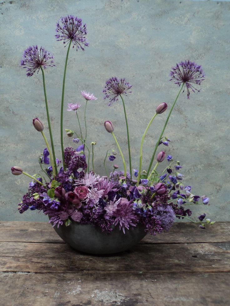 an arrangement of purple flowers in a vase