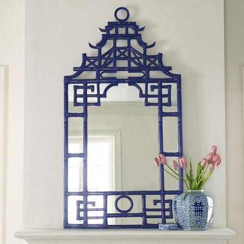 a blue and white mirror sitting on top of a shelf next to a vase with flowers