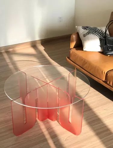 a glass table sitting on top of a hard wood floor next to a brown couch