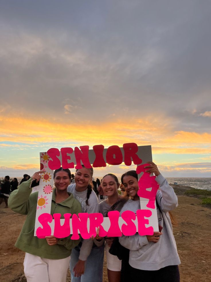 four girls holding up signs that say senior sunrise and one girl is smiling at the camera