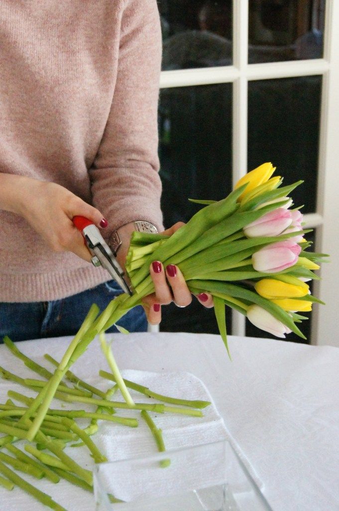 a woman cutting flowers with scissors on a table