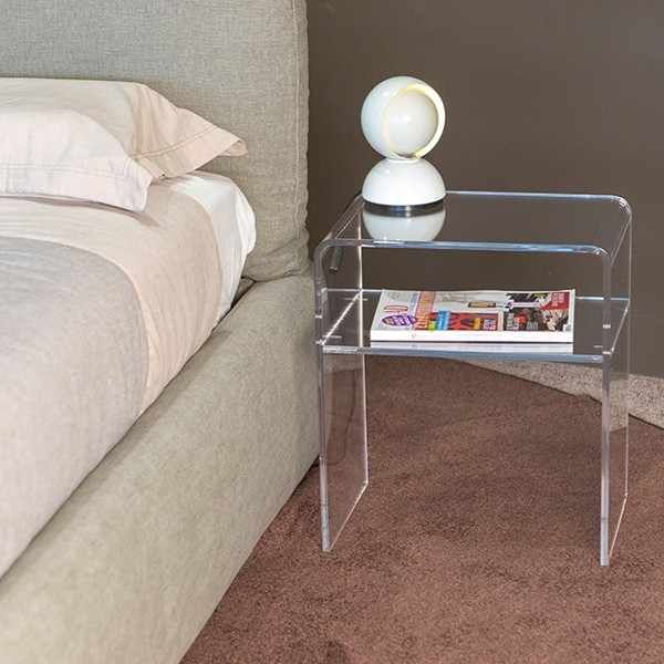 a glass table with a magazine on it in front of a bed and nightstands