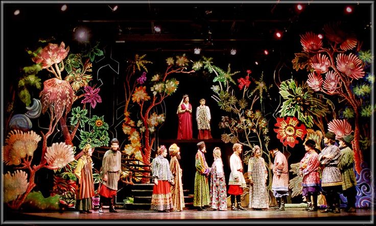 a group of people standing on top of a stage surrounded by flowers and foliages