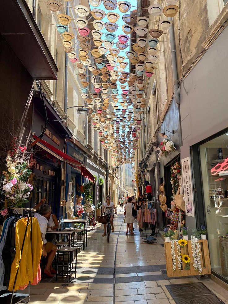 people are walking down an alley way with lots of umbrellas hanging from the ceiling