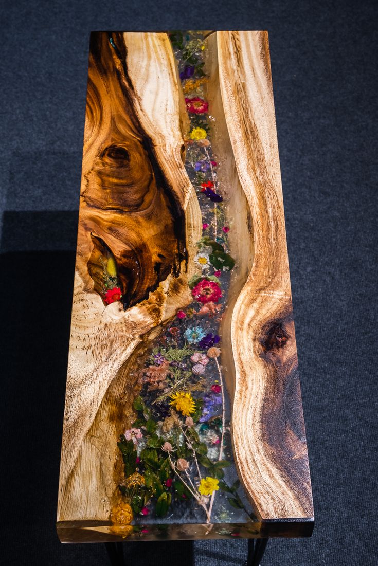 a wooden table with flowers on it in the shape of a river running through a forest