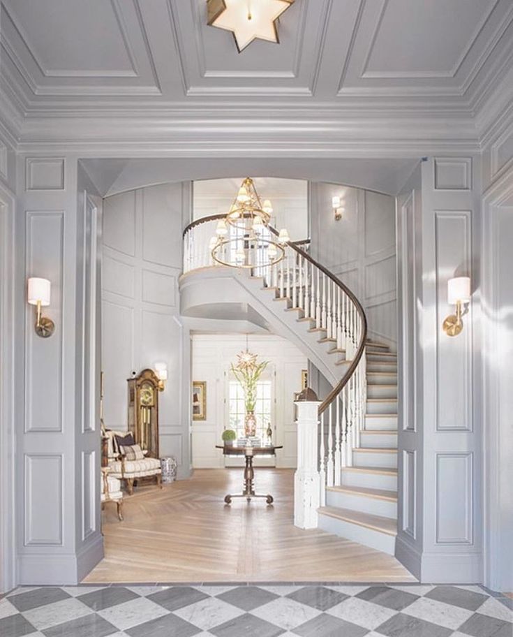 an elegant entry way with stairs and chandelier in the center is flanked by a checkered tile floor