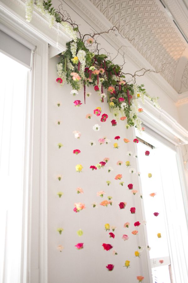 flowers are hanging from the ceiling in front of a white wall with green and red accents