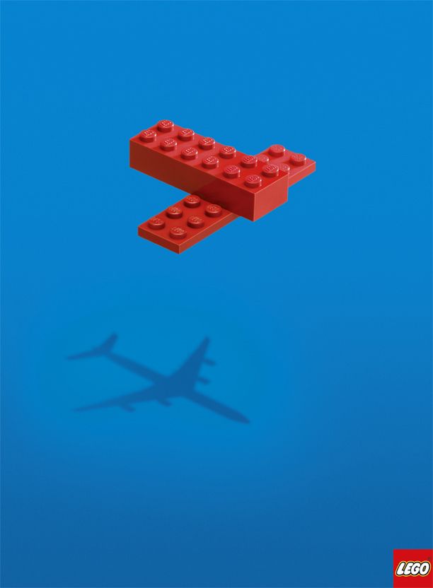 a lego airplane flying through the air with its shadow on it's back end