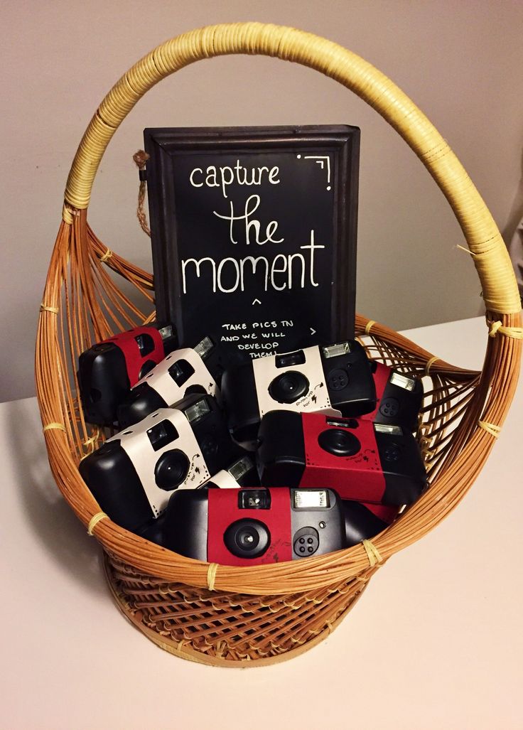 a basket filled with cameras sitting on top of a table next to a sign that says capture the moment