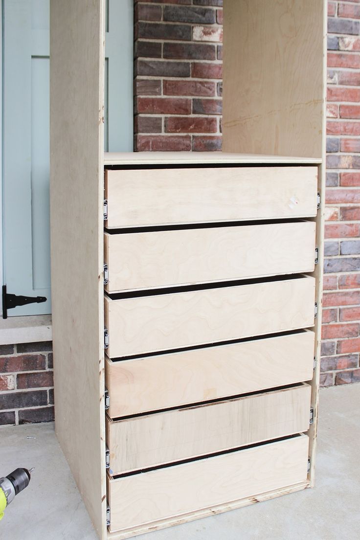 an unfinished chest of drawers in front of a brick wall